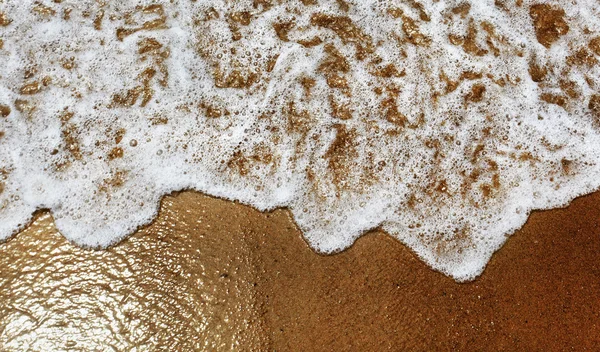 Wasser rollt auf einen Sandstrand. — Stockfoto