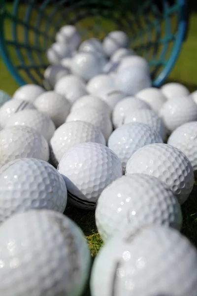 Мячи для гольфа льются из корзины на траву — стоковое фото