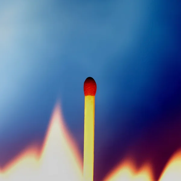 Match surrounded by flame against blue background — Stock Photo, Image