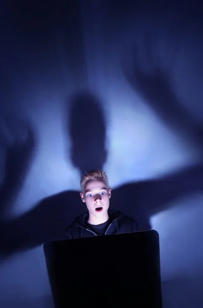 12 year old boy illuminated by the blue light of a computer moni — Stock Photo, Image