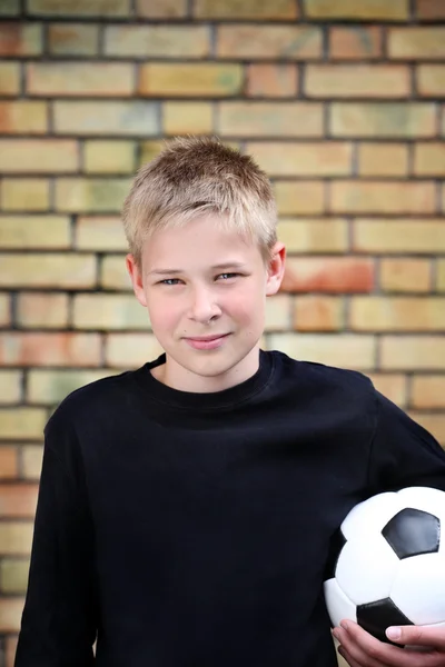 Мальчик у стены с мячом — стоковое фото