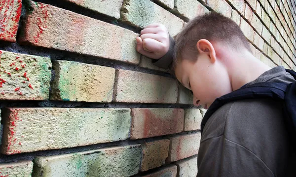 Chateado menino contra uma parede — Fotografia de Stock