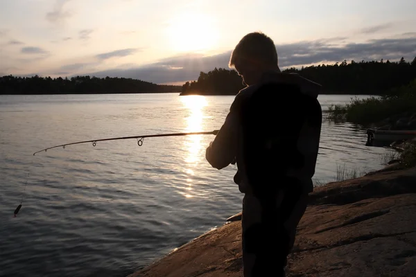 Мальчик рыбачит на восходе солнца — стоковое фото