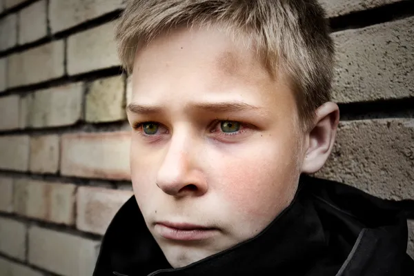 Расстроенный мальчик, прислонившийся к стене — стоковое фото