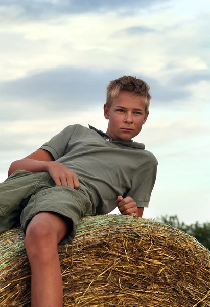 13 років старий хлопець на тюків сіна в галузі влітку — стокове фото