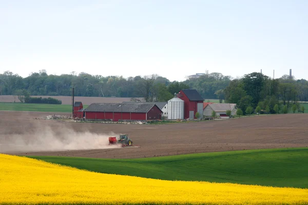 Červený traktor orat na jaře — Stock fotografie