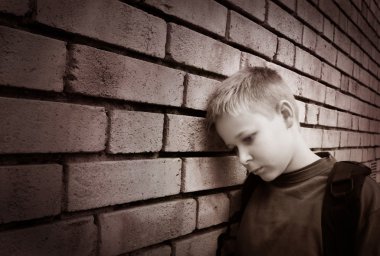 Boy leaning against a wall clipart