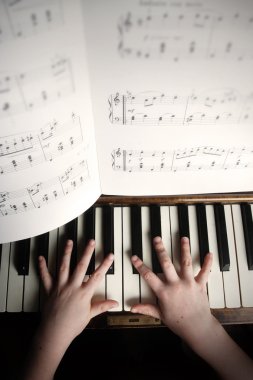 Child's hands playing on a old piano clipart