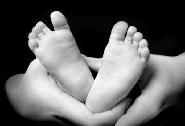 Moederdag handen holdning haar zoon's voeten — Stockfoto