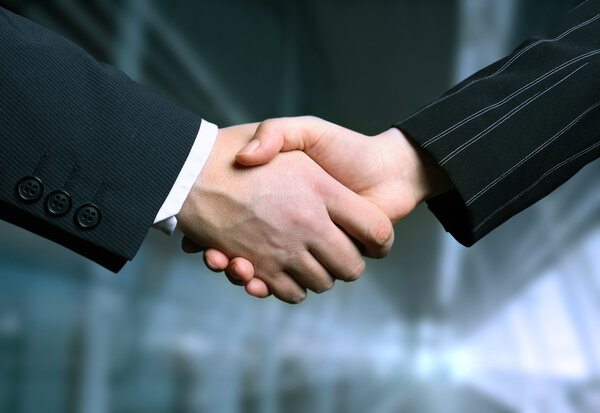 Business hand shake and a office in background