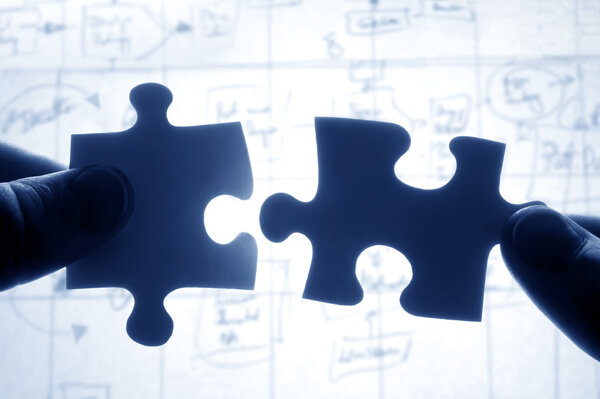 Hands trying to fit two puzzle pieces together