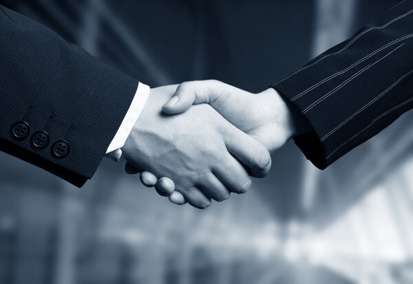 Business hand shake and a office in background