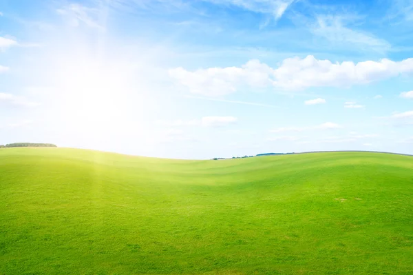 Gün ortasında güneş mavi gökyüzünün altında yeşil çim tepeler. — Stok fotoğraf