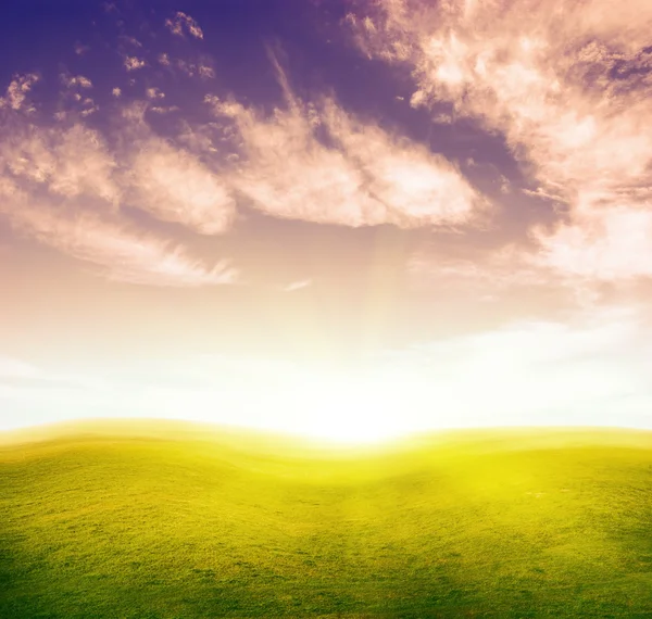 Grüne Grashügel unter farbigem Wolkenhimmel. — Stockfoto