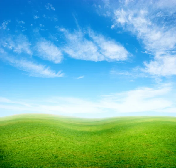Mavi gökyüzünün altında yeşil çim tepeler. — Stok fotoğraf