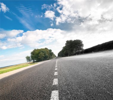 Asphalt road in green sunset meadow clipart