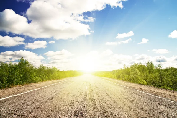 Staré asfaltové silnici zelené louce při západu slunce — Stock fotografie