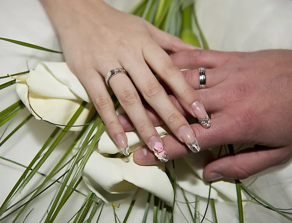 Händerna på en nyligen gift par på en bukett — Stockfoto