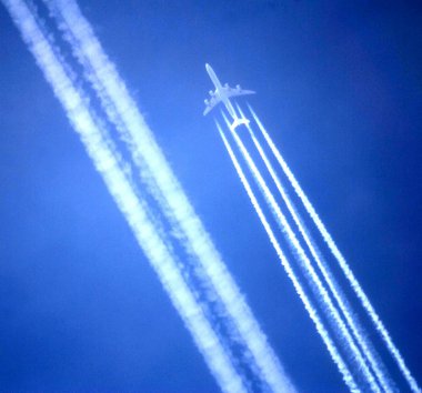 A large jet flies parallel to a vaportrail in the sky clipart