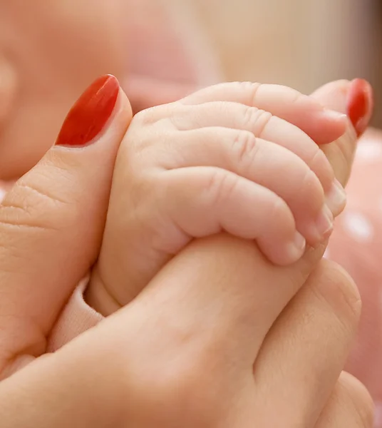 Bebê segurando mão da mãe Fotografia De Stock