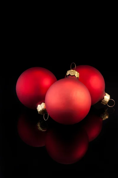 Τρεις κόκκινες μπάλες Χριστούγεννα σε μαύρο φόντο — Φωτογραφία Αρχείου
