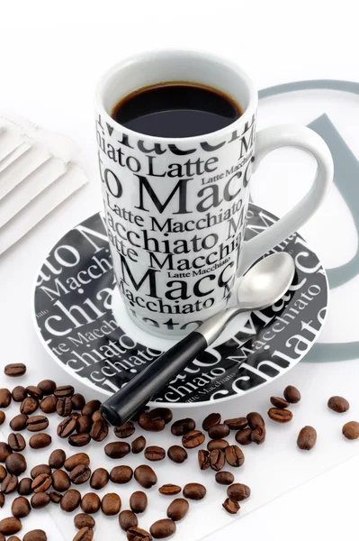 Stylish balck and white coffee mug with brown coffee beans — Stock Photo, Image