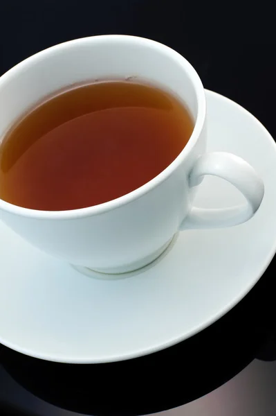 Weiße Tasse Tee auf schwarzem Hintergrund Stockbild