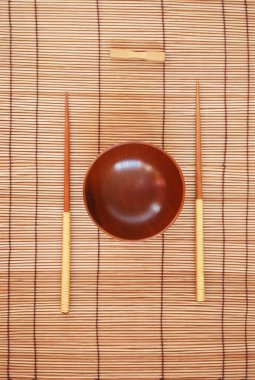 yemek çubukları ile bir bambu hasır zemin üzerine ahşap kase