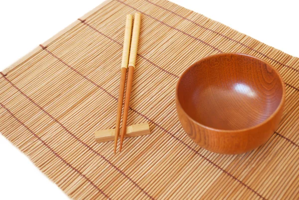 Bastoncini con ciotola di legno su sfondo stuoia di bambù — Foto Stock