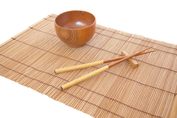 Stokjes met houten kom op bamboe matting achtergrond — Stockfoto