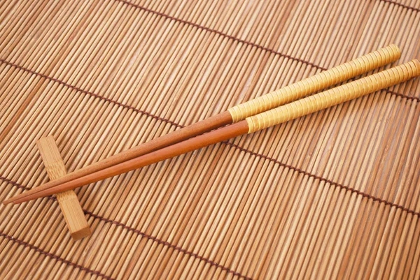 Chopsticks no fundo de esteiras de bambu marrom — Fotografia de Stock