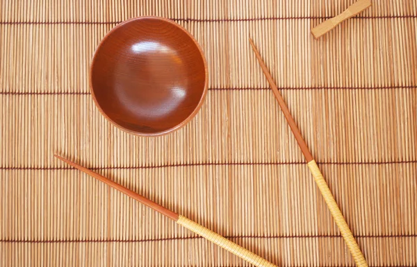 Τσοπ στικς με ξύλινο μπολ σε φόντο ψάθα μπαμπού — Φωτογραφία Αρχείου