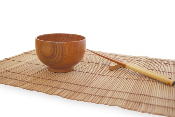Pałeczki z drewniana miska na tle maty bambusowe — Zdjęcie stockowe