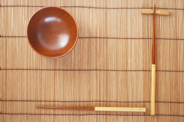 Essstäbchen mit Holzschale auf Bambusmatten Hintergrund — Stockfoto