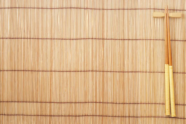 Палочки для еды на коричневом бамбуковом фоне — стоковое фото