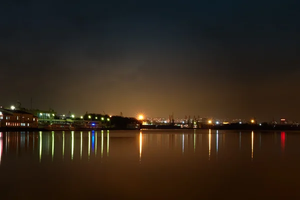 Staden på natten. Port kranar och floden — Stockfoto