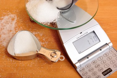 Weighing sugar on scale. clipart