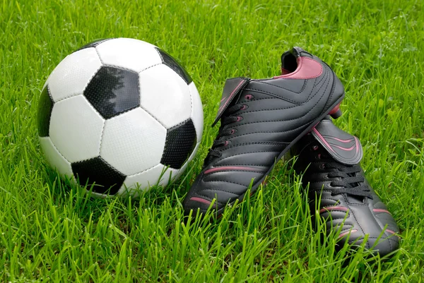 Soccer ball and shoes on grass — Stock Photo, Image