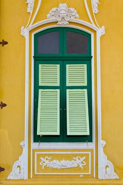 stock image The closed green window on the yellow wall