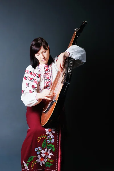 玩班杜拉的传统服饰的女人 免版税图库照片