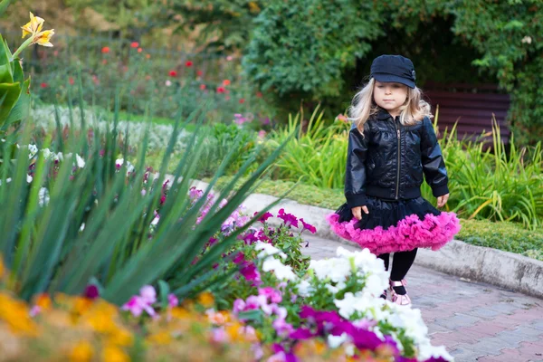Pequena menina da moda andando no parque de flores — Fotografia de Stock