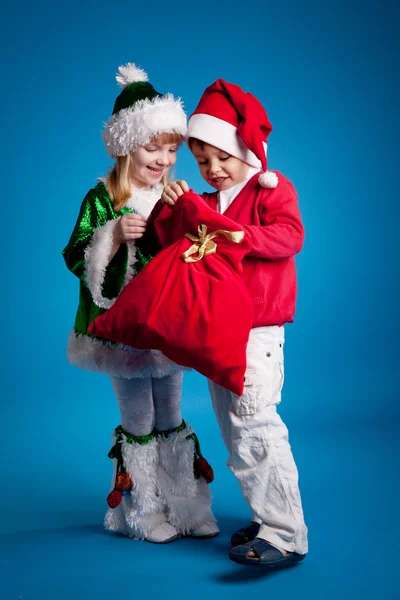Дети в новогодних костюмах с мешком подарков — стоковое фото