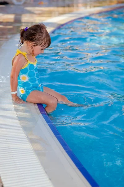Schattig klein meisje zitten in de buurt van het zwembad Stockafbeelding