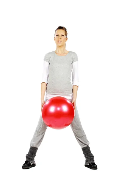 Girl holding a red ball between her legs — Stock Photo, Image