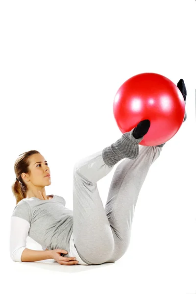 Девушка упражняется с красным мячом между ног — стоковое фото