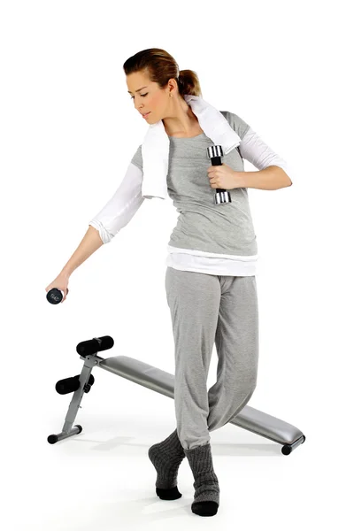 Chica haciendo ejercicio con pesas con un banco en el fondo —  Fotos de Stock