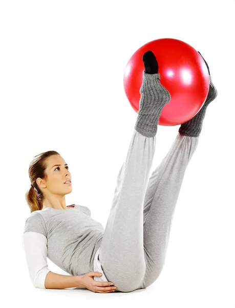 लड़की अपने पैरों के साथ एक लाल गेंद पकड़े हुए — स्टॉक फ़ोटो, इमेज
