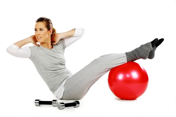 Girl sitting and exercising with a red ball — Stock Photo, Image
