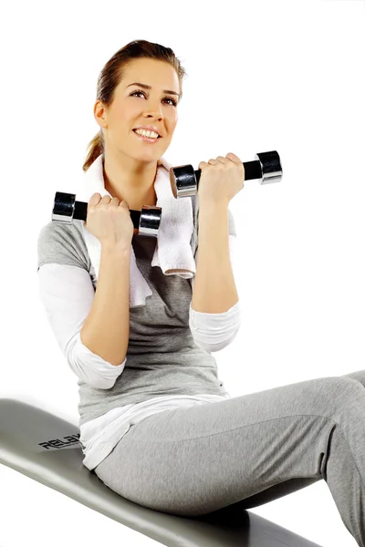 Chica sentada en un banco y haciendo ejercicio con pesas — Foto de Stock