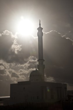 A mosque in Gibraltar with the sun breaking through the clouds. clipart